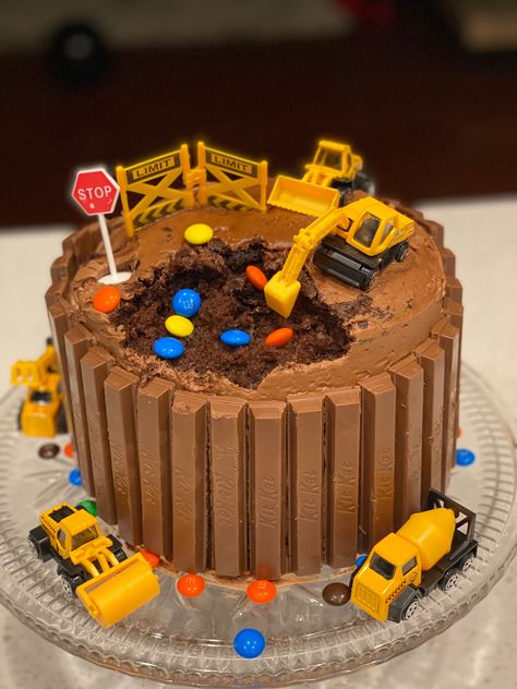 Chocolate digger cake surrounded by Kit Kat’s and M&Ms Tonka Truck Birthday Party Cake, Diggers Birthday Cake, Digger Themed Birthday Cake, Chocolate Digger Birthday Cake, Construction Birthday Cake 4, Construction Worker Birthday Cake, Easy Construction Birthday Cake, Diy Digger Cake, Construction Dirt Cake