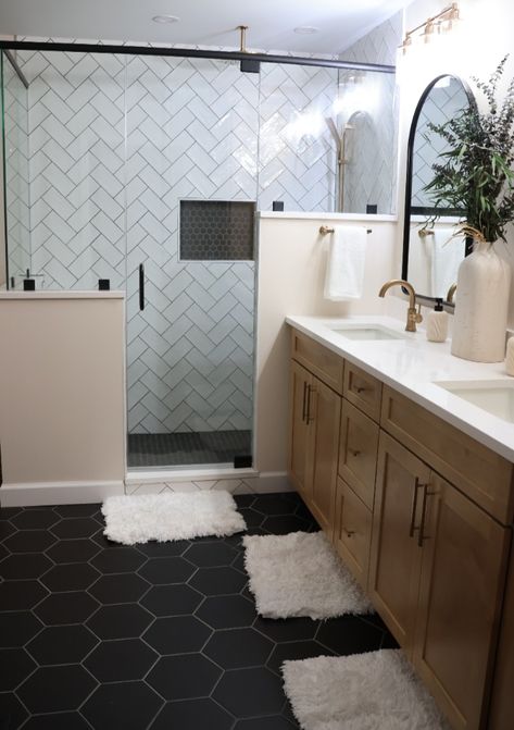 This beautiful bathroom features hexagon floor tiles with coordinating hexagon mosaic in the shower inset. The dark tiles are nicely juxtaposed against the white subway tiles in a herringbone pattern. Subway Tile Bathroom Dark Floor, Black Hexagon Flooring Bathroom, Bathroom Dark Hexagon Tile Floor, Dark Tile Bathroom Floor White Walls, Dark Floor Shower Tile, Master Bath With Black Floor, Bathroom Remodel Hexagon Tile Floor, Black Hexagon Tile Bathroom Floor Ideas, Bathroom With Black Hexagon Floor Tile