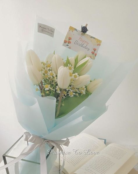 bouquet with white tulips, daisies, and assorted greenery, in pastel blue paper, tied with a white ribbon. Tulips And Daisy Bouquet, White Tulips Bouquet, Fruit Flower Basket, White Tulip Bouquet, Daisy Bouquet, Ribbon Bouquet, Blue Tulips, Tulip Bouquet, White Tulips