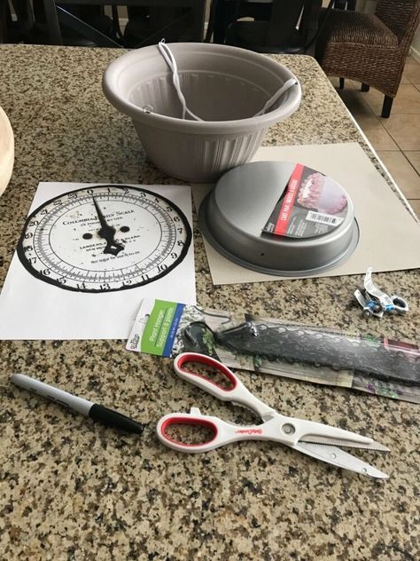 Farmhouse style is really popular, so I thought I'd make a hanging farmhouse kitchen scale to go with my counter scale. It's perfect to hang in the corner and use for holding fruits.  Start it off by tracing a circle using a cake pan. This will be used as the backing for the clock face and to help it stand upright. Next, cut the scale face out. I used the same face that I used for my counter scale. I then glued it to the cardboard. If you can, you can just print the face out on card st… Hanging Scale Decor Ideas, Eclectic Plates, Diy Scale, Kitchen Art Ideas, Wall Vase Decor, Farmhouse Kitchen Diy, Bronze Spray Paint, Farmhouse Fall Wreath, Hanging Scale