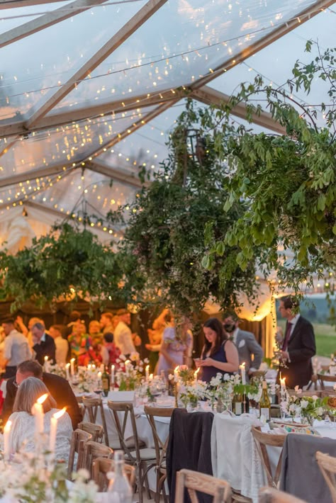 A clear marquee pictured at dusk, dressed for a wedding.   With a canopy of fairy lights,   long banquet tables with soft pretty florals and lots of candlelight. Marquee Layout Wedding, Colourful Marquee Wedding, Clear Span Marquee Wedding, Marquee Garden Party, Garden Wedding Marquee, Clearspan Marquee Wedding, Rustic Wedding Marquee, Wedding Marquee Flowers, Marquee Fairy Lights