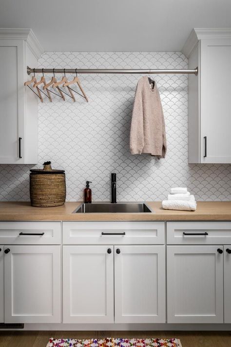 Stylish laundry room design with white cabinetry, wood countertop, modern backsplash tile, and hanging rod for drying clothes. A perfect combination of functionality and contemporary style.Laundry room with white cabinets, wood countertop, backsplash tile, and drying rod.#LaundryRoomDesign #HomeOrganization #InteriorDesign #HomeRenovation #ClarkAndAldinePin Light Gray Laundry Room Cabinets, Laundry Room Ideas White Cabinets, Butcher Block In Laundry Room, Tile In Laundry Room, Laundry Room Tile Backsplash, Laundry Room White Cabinets, Laundry Room With White Cabinets, Laundry Backsplash, Modern Backsplash Tile