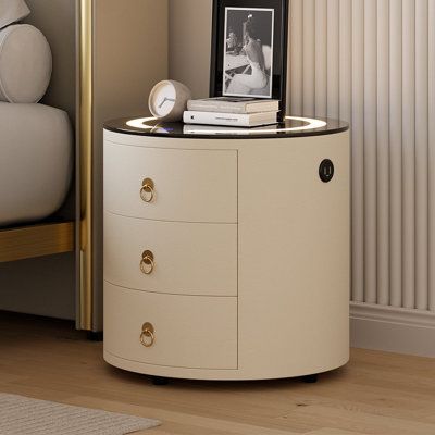 This nightstand features a tempered glass top and high-quality PU leather upholstery for luxury. It includes a touchscreen control panel for easy customization, wireless charging for devices, and a sensor LED-dimmable light that adjusts to your presence. A built-in Bluetooth speaker system provides a rich audio experience, helping to soothe, relax, or energize your mood with music. Everly Quinn | Everly Quinn Modern Off-White Round Nightstand w/ Light And Wireless Charging And Speakers And USB P Round Nightstand, Modern Nightstand, Speaker System, Everly Quinn, Control Panel, Leather Upholstery, Wireless Charging, Bluetooth Speaker, Touch Screen