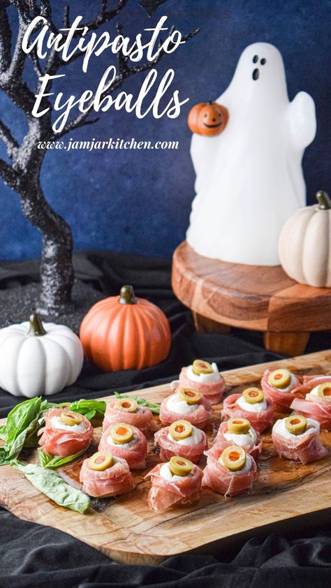 wood plate with anitpasto eyeballs (mozzarella wrapped in prosciutto and half a green olive to resemble an eye). the background has a ghost and pumpkins Halloween Charcuterie Board, Halloween Charcuterie, Mozzarella Balls, Bbq Meatballs, Jar Kitchen, The Jam, Green Olives, Balsamic Glaze, Halloween Food For Party