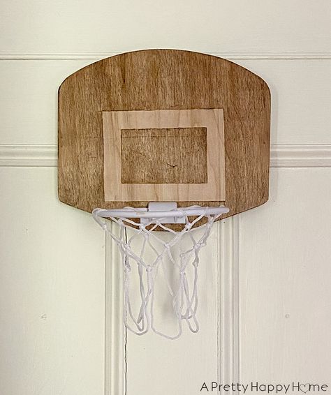 Create a wood backboard for an over-the-door basketball hoop by removing the old plastic backboard and attaching a wood one. Over The Door Basketball Hoop, Diy Backboard, Diy Basketball Hoop, Door Basketball Hoop, Basketball Centerpieces, Diy Basketball, Boy Bedrooms, Basketball Rim, Basketball Backboard