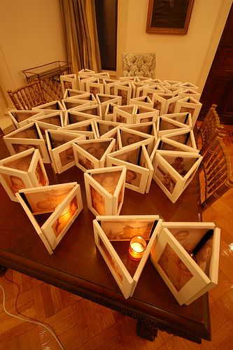 Cheap frames, spraypaint, and ducktape (I think I would use white to match the frames). Print photos on vellum, and staple or tape them into the frame. Place a candle in the middle for a personalized, glowing centerpiece. Cute! Picture Frame Centerpiece Wedding, 50th Wedding Anniversary Party Ideas Decorations Photo Centerpieces, Photo Frame Centerpiece Ideas, 90th Birthday Guest Book Ideas, Wedding Photo Centerpieces, Pictures As Centerpieces, Elegant Centerpiece Ideas, Picture Centerpieces Wedding, Centerpieces 50th Anniversary