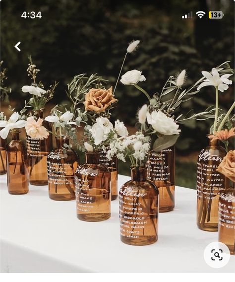 Amber Glass Bottles Wedding, Amber Glass Vase With Flowers, Glass Bottle Seating Chart Wedding, Bourbon Wedding Centerpieces, Brown Glass Bottles Wedding, Amber Glasses Wedding Table, Amber Jar Centerpiece, Glass Bottle Seating Chart, Amber Wedding Table Decor