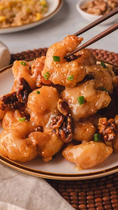 Plate of honey walnut shrimp garnished with green onions, with chopsticks picking up a piece. Honey Walnut Shrimp Panda Express, Panda Express Walnut Shrimp Recipe, Panda Express Walnut Shrimp, Walnut Shrimp Panda Express, Panda Express Honey Walnut Shrimp Recipe, Honey Walnut Shrimp Recipe Panda Express, Panda Express Honey Walnut Shrimp, Walnut Shrimp Recipe, Making Honey