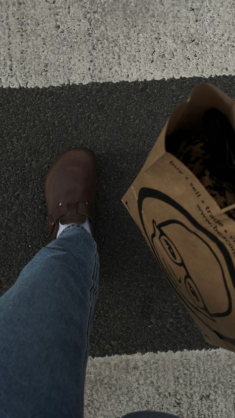 bird’s eye view shot of feet walking on a crosswalk. maia is wearing dark brown oiled leather birkenstocks with white socks and light-wash levi’s jeans. a brown paper bag with clothes inside is on the side of the image. Brown Birks Outfit, Black Leather Boston Birkenstocks Outfit, Brown Leather Birkenstocks Outfit, Leather Boston Clogs Outfit, Oiled Leather Birkenstocks Outfit, Dark Brown Boston Clogs Outfit, Leather Boston Birkenstocks, Mocha Boston Birkenstock Outfit, Brown Birkenstock Clogs Outfit