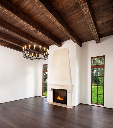 Spanish Mediterranean Elegance Plaster fireplace, custom iron chandelier, hand painted wood beams, wood floor | Santa Barbara Mediterranean Mediterranean Fireplace, Spanish Mediterranean Homes, Colonial Revival House, Painted Beams, Santa Barbara Style, Spanish Mediterranean, Bronze Fixtures, Dark Wood Cabinets, Iron Chandeliers