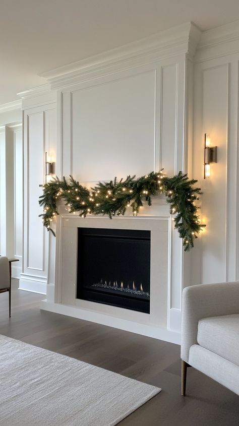 Elegant fireplace adorned with a simple Christmas garland, twinkling lights, and warm lighting for a cozy holiday atmosphere. Christmas Tv Mantle Decor, Fireplace Mantel Styling Ideas, White Christmas Fireplace Decor, Apartment Fireplace Decor, Sides Of Fireplace Decor, Christmas Mantle With Tv, Neutral Mantle Decor, Tv Mantle Decor, Mantel Decorating Ideas With Tv