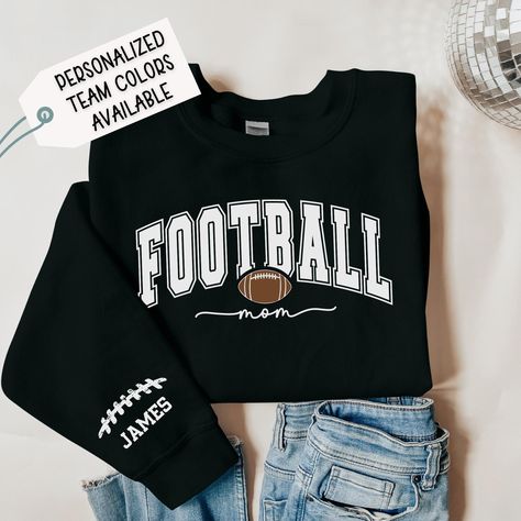 Black Personalized Football Mom Sweatshirt with Player's Custom Name, Football Mama Hoodie, Football Mom Hoodie with Son's Name Listing pricing is for one sleeve only. If you would like two names on two different sleeve, please visit: https://www.etsy.com/listing/1769663771/black-personalized-football-mom The Gildan 18000 sweatshirt is made from a heavy blend of cotton and polyester, making it perfect for any situation. The ribbed knit collar will keep your neck warm, and the garment is machine- Football Hoodie Ideas, Football Mom Outfits, Football Mom Outfit, Plush Making, Football Hoodies, Mom Crewneck, Football Sweater, Mama Hoodie, Football Theme