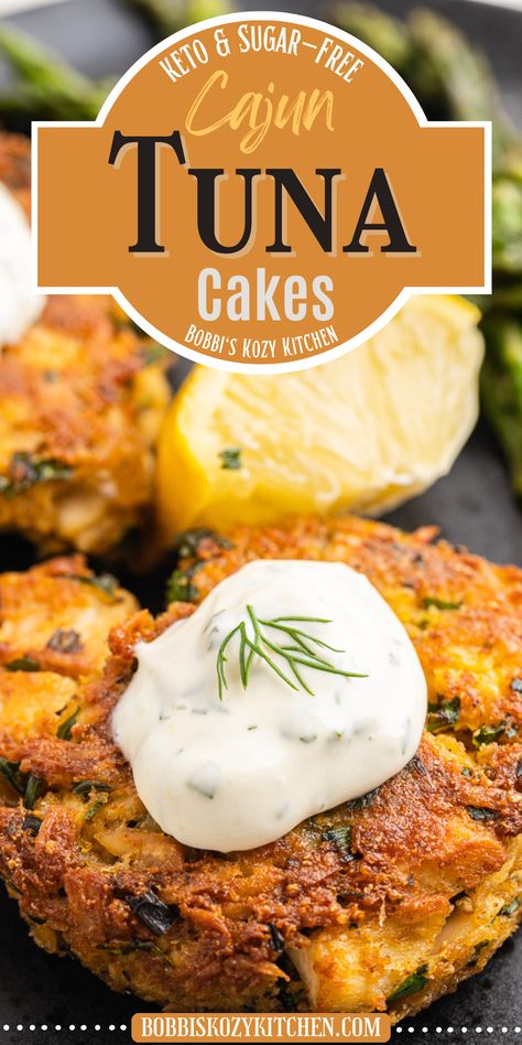 Two Keto Cajun Tuna Cakes on a black plate, topped with remoulade sauce and garnished with fresh dill. Served with lemon wedge and grilled asparagus, a delightful low-carb and gluten-free meal. Keto Tuna Fish Recipes, Gluten Free Tuna Melt, Gluten Free Tuna Cakes, Keto Tuna Melt Patties, Keto Spicy Tuna, Cajun Spices, Keto Fish, Tuna Patties, Tuna Cakes