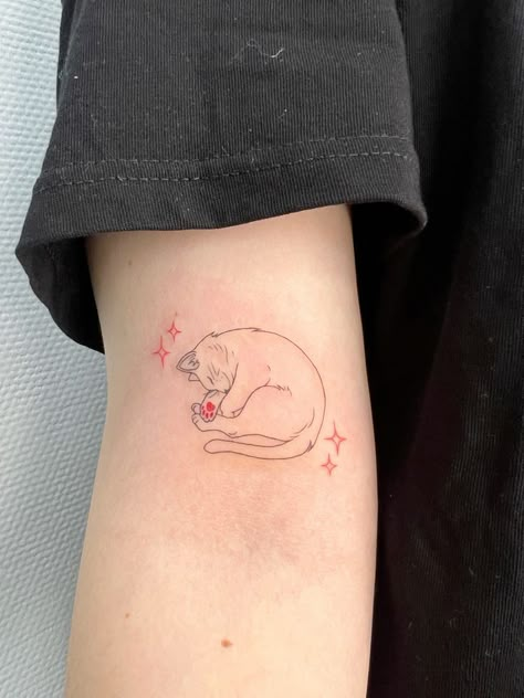 tattoo Minimalist cat tattoo on arm with pink stars, featuring a sleeping cat curled up with a pink paw print. | Sky Rye Design Sleeping Cat Tattoo, Cat Paw Tattoo, Cat Memorial Tattoo, Cat Paw Print Tattoo, Minimalist Cat Tattoo, Cat Paw Tattoos, Grandma Tattoos, Michael Tattoo, Pet Memorial Tattoo