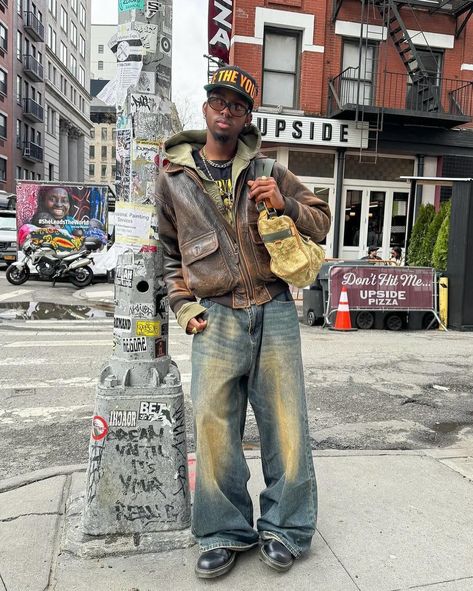 Vintage Vibe 🍩 How about his color? 📸 @knawtkai 🇺🇸 🧢Cap : free the youth 👔Hoodie : trendtvision 👞Shoes : dr.martens 👜Bag : louis vuitton Embodying the vintage vibes of American streets, this man’s outfit exudes timeless coolness. The combination of the vintage brown leather jacket and washed baggy jeans sets the tone, while the ‘Trendtvision’ khaki zipped hoodie and black printed shirt add depth to the ensemble. Elevating the look further, the ‘Dr. Martens’ black boots and ‘Free the Y... Dr Martens Brown Outfit, Brown Jean Jacket Outfit, Brown Shoes Outfit Men, Brown Shoes Outfit, Brown Jean Jacket, Brown Leather Jacket Outfit, Vintage Brown Leather Jacket, Dr Martens Outfit, Jean Jacket Outfits