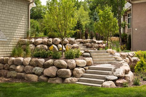 Two tiered boulder backyard boulder wall terraces. Rock Wall Landscape, Boulder Retaining Wall, Backyard Retaining Walls, Rock Retaining Wall, Sloped Backyard Landscaping, Home Exterior Design, Large Backyard Landscaping, Landscaping On A Hill, Sloped Backyard