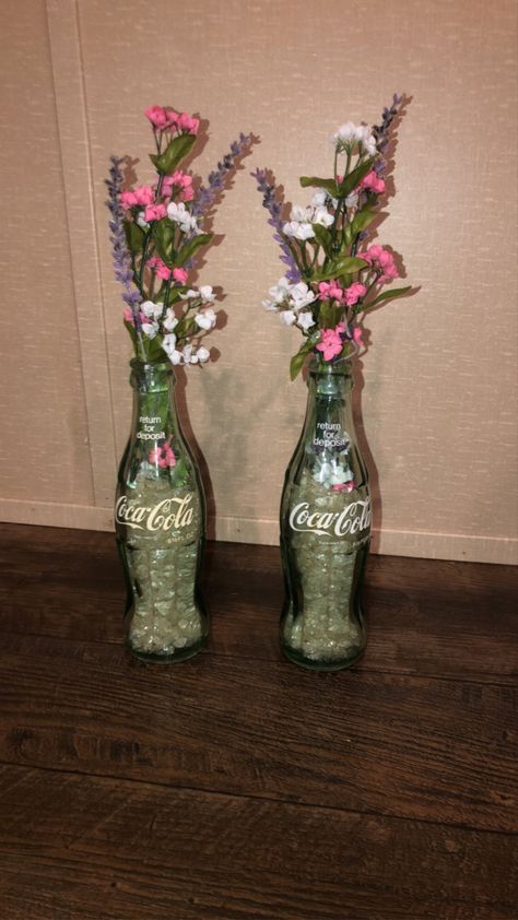 I got these old coke bottles from the back yard and the flowers from Hobby Lobby!! Glass Soda Bottle Crafts, Glass Coke Bottle Crafts, Coke Bottle Decor, Glass Coke Bottle Centerpieces, Plants In Coke Bottles, Flowers In Coke Bottles, Coke Bottle Crafts, Old Coke Bottles, Soda Bottle Crafts