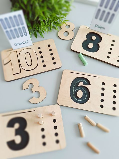 A set of mathematical boards is perfect for manipulative games, practicing fine motor skills and eye-hand coordination. It supports education and recognition of numbers and learning to count.  The set includes:  - wooden boards 1-10 (with chalk paint, so your little one can practice writing with chalk many times and learn the shapes of numbers)  - wooden numbers 1-10 (they are removable so they can be placed on correct boards or used without them to play) - piece of chalk  - 55 wooden pegs  - fabric bag for convenient storage of pegs   Dimensions of wooden boards : 16 x 10 cm  Disclaimer: this product is not a toy and it requires adult supervision when being used by a child.  The product is handmade which makes it unique (the colour or patterns on the wood may slightly differ from the phot Counting Board, Maths Learning, Diy Montessori Toys, Wood Laser Ideas, Learning To Count, Wooden Educational Toys, Wooden Numbers, Wooden Boards, Homemade Toys