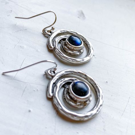 This pair of hammered silver-tone spiral earrings set with flashy blue labradorite pays homage to our home galaxy, the Milky Way. A more bohemian take on our celestial jewelry stylings, this statement jewelry is sure to turn heads with every colorful flash of the stone. Celebrate our cosmic home in style! Pairs perfect Space Jewelry, Spiral Galaxy, Spiral Earrings, The Milky Way, Jewelry Techniques, Celestial Jewelry, Silver Dangle Earrings, Blue Labradorite, Handcrafted Earrings