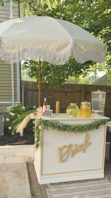 white mobile bar beverage station with umbrella setup for events. Greenery decor. Mobile Bar Aesthetic, Mobile Bar Set Up, Wedding Drinks Station, Satellite Bar, Garden Party Bar, Wedding Bar Cart, Mobil Bar, Serving Station, Trailer Bar