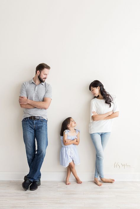 Fun Family image of Mom and Dad looking at their daughter between them leaning against the wall of our natural light studio as their four-year-old daughter does the same and looks up at Mom near Atlanta, Georgia. Mom And Daughter Sitting Poses, Studio Maternity Shoot With Daughter, Mother And Daughter Studio Photography, Father And Daughter Studio Photography, Parent And Child Poses, Father Daughter Photos, Father Daughter Photography, Toddler Poses, Dad Daughter