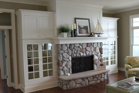 Beach Stone Fireplace, Rock Fireplace Surround, River Stone Fireplace, Built Ins Around Brick Fireplace, Stone Fireplace Windows On Each Side, Curved Built Ins Around Fireplace, Round Stone Fireplace, Round Rock Fireplace, River Rock Fireplace Ideas