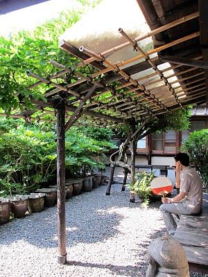 Another extremely simple arbor, a two-post lean-to against side of building with a climbing vine going up far post Bamboo In The Garden, Simple Arbor, Bamboo Patio, Side Of Building, Bamboo Arbor, Arbor Trellis, Side Garage, Lean To Conservatory, Curved Pergola