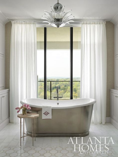 The primary bathroom’s deep soaking tub is a spa-like getaway high above the trees. The floor-to-ceiling windows are framed by sheer Casamance fabric. Tub In Front Of Window, Casamance Fabric, Atlanta Homes And Lifestyles, Stone Porches, Window Treatments Sheer, Spa Bathtub, Stand Alone Tub, European Cottage, Deep Soaking Tub