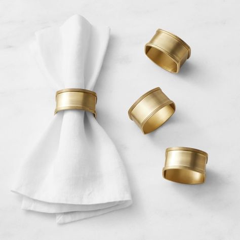 These brass napkin rings have a timeless appeal that works with table settings year-round. The antique brushed-gold finish has a warmth and soft luster that contrasts beautifully with solid and patterned table linens. The rings are hand-shaped on a mold then lacquer-finished for extra durability. Set of four. Crafted of 100% brass with antique finish. Coated in clear lacquer for extra resilience. Gold Table Accessories, Napkin Ring Place Cards, Brass Napkin Rings, Napkins With Rings, Gold Wedding Table Setting, Napkin Ring Ideas, Napkin Ring Folding, Modern Napkin Rings, Napkins Rings