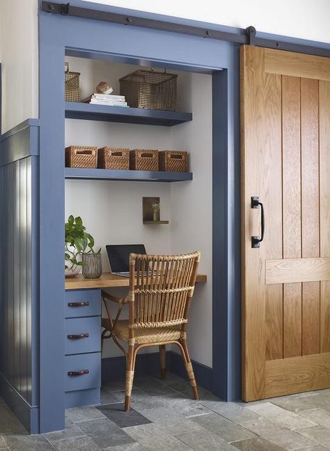 Fitted in a closet behind a wooden sliding barn door on rails, a blue mudroom desk is accented with a wood top and paired with a rope and rattan desk chair. Closet With Desk, Mudroom Desk, Blue Mudroom, Kristina Crestin, Cottage Laundry Room, Rattan Desk, Closet Desk, Desk Nook, Tiny Home Office