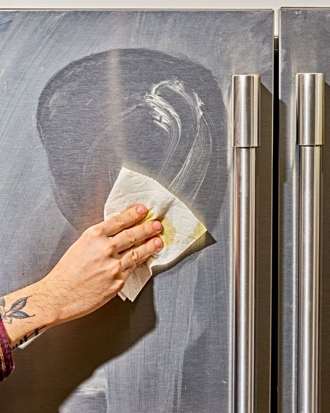 a hand wiping down a stainless steel refrigerator Best Way To Clean Stainless Steel Fridge, Best Way To Clean Stainless Appliances, Diy Stainless Steel Cleaner Appliances, How To Clean Stainless Steel Appliances, Clean Stainless Steel Fridge, Clean Stainless Appliances, Cleaning Stainless Steel Fridge, Stainless Steel Appliance Cleaner, Diy Stainless Steel Cleaner