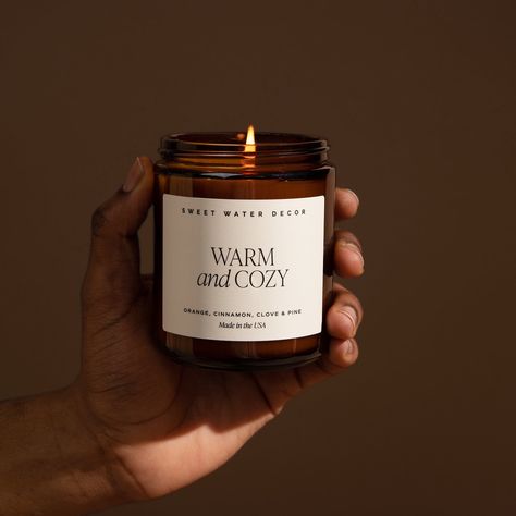 About this Item Warm + Cozy was voted "Best Fall Candle Overall" by Forbes Vetted (2022)! Our Warm and Cozy soy candle will take you to a place by a warm fire, with cozy blankets, in your PJ's, enjoying the scents of the season. With notes of pine, orange, cinnamon, cypress, and fir - it makes a perfect candle to burn during the holiday season. Infused with natural essential oils: orange, cinnamon, clove, vetiver, pine Fragrance notes Top: Orange Peel, Cinnamon, Ginger Middle: Clove, Cypress Bas Patchouli Candle, Water Decor, Clove Leaf, Vanilla Sandalwood, Amber Candle, Sweet Water, Fall Candle, Sandalwood Scent, Candle Care