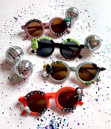 "Where are all my \"Spooky Dudes\"?!! These HALLOWEEN SUNNIES are for you!! These are so stinking adorable-- Each pair is handcrafted by me. Using various beads & Charms!!   👻☠️ *4 options available-- 🦇  Choose your style:  1. RAD TO THE BONE 2. BOO CREW 3. CREEP IT REAL 4. SPOOKY DUDE * Anti-Glare * UV Protection (UVA & UVB) * Durable and shatterproof  * They open and close smoothly  * Each item is made to order and will be ready to ship in 5-7 business days! If you need your order sooner. Please check out my \"RUSH ORDER OPTION\".  https://www.etsy.com/EyeCandyandFluff/listing/1286351273/rush-my-order-please *SHOP DISCLAIMER/WAIVER!  * Do NOT let your child put the sunglasses in their mouth as beads can become detached.    Always monitor and supervise while children are wearing these. Trendy Halloween Festival Sunglasses, Fun Black Halloween Sunglasses, Plastic Sunglasses For Halloween Party, Fun Party Sunglasses For Halloween, Halloween Party Sunglasses In Plastic, Halloween Party Plastic Sunglasses, Fun Halloween Party Sunglasses, Fun Festival Sunglasses With Tinted Lenses, Playful Adjustable Sunglasses For Party