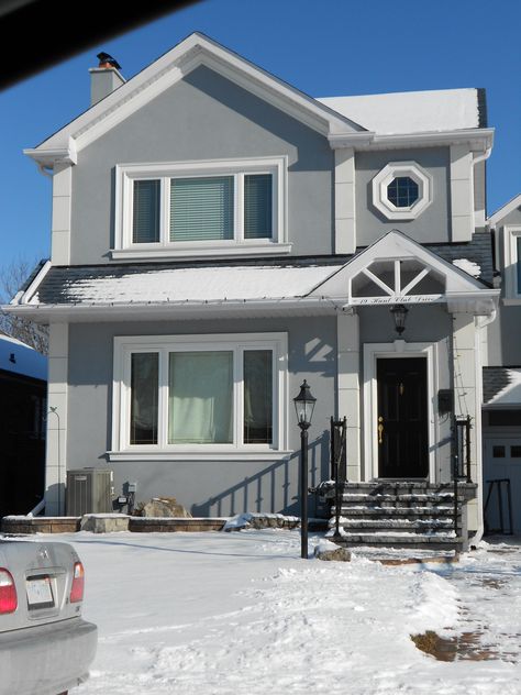 This one's my favourite. I love the grey stucco, the black roof and door, the white embossments and trim. And I really like the little octagonal window. Add a porch and this one's the winner! Light Grey And White House Exterior, Gray And White Exterior House Colors, Light Grey House Exterior White Trim, Gray And White House Exterior, Light Grey Exterior House Colors, Grey Stucco House Exterior, Octagonal Window, Grey House White Trim, Grey Stucco