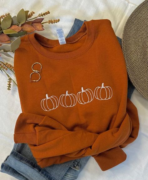 Cool Fall days and Pumpkin Patches, that's what we love!  The days become shorter but they sure seem to slow down.  Our simple pumpkin outline crew in the beautiful burnt orange is the perfect way to show you love the season in perfect minimalist style.  You will stay cozy and warm while looking super cute!   Pair with your favorite jeans, or size up one and grab your comfy leggings!  Features: 50% USA cotton, 50% polyester Pill-resistant air jet yarn Made with 50% sustainably and fairly grown U Pumpkin Sweatshirt Diy, Fall Graphic Sweatshirt, Pumpkin Embroidery Designs, Cute Fall Sweatshirts, Embroidered Halloween Sweatshirt, Fall Embroidered Sweatshirts, Fall Sweatshirt Ideas, Fall Pullovers, Simple Fall Style