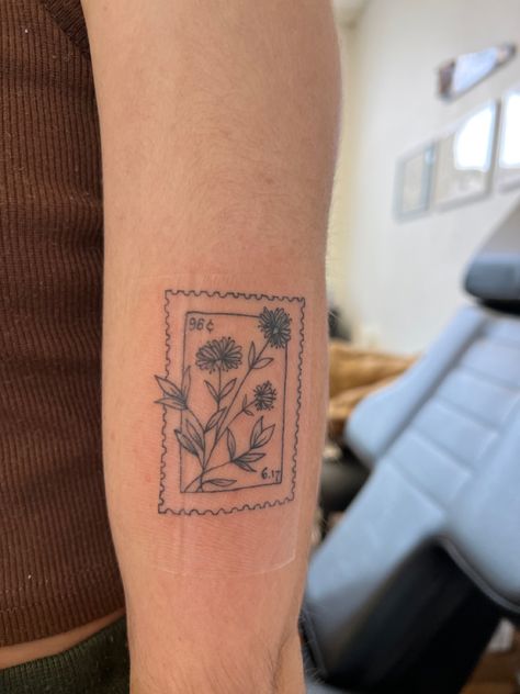 Photo of a tattoo that is inspired by a postage stamp. Flower Stamp Tattoo Ideas, Small Stamp Tattoo Ideas, Peony Stamp Tattoo, Wildflower Stamp Tattoo, Honeysuckle Stamp Tattoo, Flower Polaroid Tattoo, Hollyhocks Flowers Tattoo, Post Stamp Flower Tattoo, Flowers In A Box Tattoo