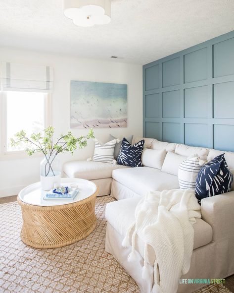 A TV room with blue board and batten grid wall with linen sectional, round coffee table and coastal wall art with a beach scene. Diy Accent Walls, Light Blue Grey Paint, Blue Gray Paint Colors, Blue Accent Walls, Blue Gray Paint, Diy Accent Wall, Accent Walls In Living Room, Grey Paint Colors, Wallpaper Accent Wall