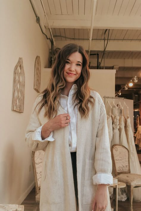 Carolynn Thielges is standing and smiling for the photo. Her long brown hair is crimped and she's wearing a white collared button down with a tan cardigan. Button Up Cardigan Outfit Work, Cardigan Over Button Down Shirt, Button Up With Cardigan, Cardigan With Collared Shirt, Light Beige Cardigan Outfit, Blouse And Cardigan Outfit, Button Down With Cardigan, Oversized Cream Cardigan For Work, Chic Collared Beige Cardigan