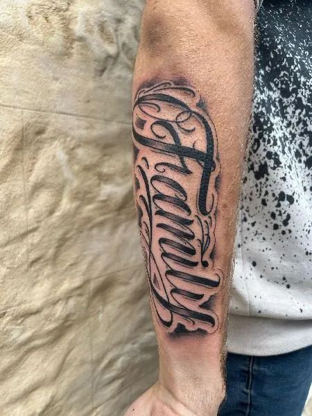 Family Forearm Tattoo 1 Men’s Forearm Tattoo Ideas Family, Cursive Tattoo On Forearm, Jones Tattoo Name, Word Family Tattoo Ideas, Forearm Tattoos Family, Forearm Word Tattoos Men, Forearm Lettering Tattoo Men, Family Arm Tattoo Men, Name Arm Tattoo Men