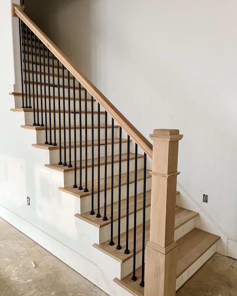 A neutral room features white stairs and oak wood treads. The oak is coordinated with a matching wood banister. Black railings contrast with the muted palette of the space. Wood Staircase Ideas, White And Wood Staircase, Wood Banister, Oak Banister, Black And White Stairs, Redo Stairs, Black Staircase, Metal Stair Railing, White Staircase