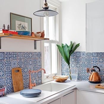 The owners decided to perk up the space by switching out the grey tiles for a rich blue decorative design. They also installed a copper tap, and chose warm-coloured accent throughout, to being a welcoming glow to the kitchen. Blue And White Spanish Kitchen, Talavera Interior Design, Talavera Backsplash Kitchen, Mexican Kitchen Decor Ideas Hacienda Style, Mexican Bungalow, Talavera Kitchen Decor, Kitchen Spanish Style, Hacienda Kitchen Decor, Talavera Tile Kitchen