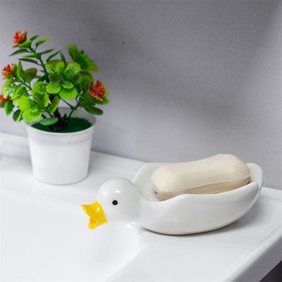 Transform your bathroom into a whimsical haven with our Quack Quack Soap Saver, a charming ceramic duck-shaped soap dish that's as delightful as it is practical. With its self-draining design, this soap holder ensures your soap stays dry and your space stays clean, while its stylish, durable build promises a long-lasting addition to your home decor. Perfect for any bathroom or kitchen, it's a small change that makes a big difference in your daily routine. Gracie Oaks | Gracie Oaks Aziria Bathroo Paint Pottery, Ceramic Duck, Diy Pottery Painting, Quack Quack, Cute Duck, Soap Saver, White Pottery, Diy Pottery, Bath Storage