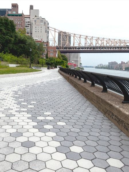 A promenade between two existing parks overlooks the East River and Queensboro Bridge in New York. Conscious of the negative impacts of stormwater runoff, permeable pavers were used in the design and create a unique gradient paving pattern with Unilock Permeable Hex / City Park Paver in three different colors. The color gradient flows along the promenade creating curves that mimic the adjacent river. #landscapearchitecture #geometricpaving Paving Design Landscape, Paving Pattern Landscape, Pavement Design Paving Pattern, Parking Pavers, Simple Concrete Patio, Pavers Pattern, Pavement Pattern, Brick Pavement, Permeable Pavement