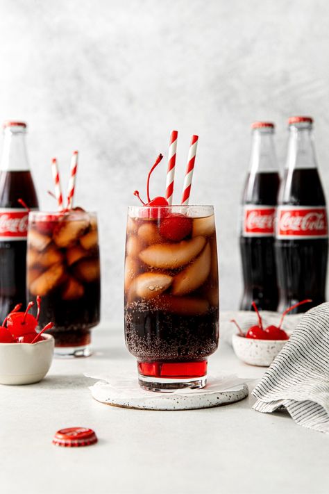 An old-fashioned Roy Rogers drink served in a tall glass with maraschino cherries and straws. Cold Drink Photography, Coca Cola Photography, American Theme Party, Roy Rogers Drink, Coca Cherry, Coca Cola Aesthetic, Peppermint Fizz, Drink Pictures, Cold Weather Drinks