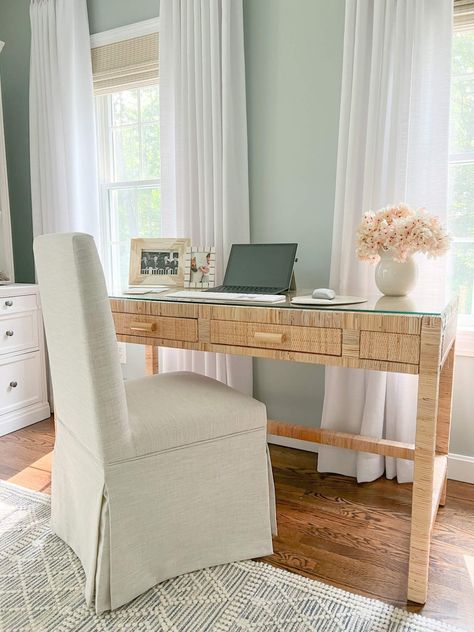 closeup of rattan desk with glass top and computer sitting on top with linen fabric desk chair Fabric Desk Chair, Coastal Bedroom With Desk, Linen Desk Chair, Coastal Desk Chair, Rattan Desk Chair, Home Office Coastal, Boho Office Room, Coastal Office Decor, Coastal Desk