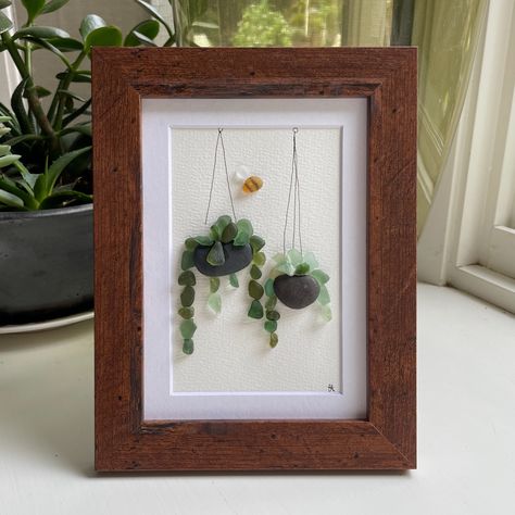 This 5 x 7 inch framed sea glass art picture features two hanging plants made from genuine sea glass, pottery & pebbles with a cute little sea glass bee buzzing about.  Designs may vary. Sea Glass Art Projects, Beach Glass Crafts, Beach Pottery, Seashell Wall Art, Glass Art Pictures, Glass Art Projects, Silver Sea, Sea Glass Crafts, Beach Wall Decor