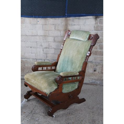 Antique Victorian platform rocking armchair.  Made of walnut featuring Eastlake styling with turned foliate and wheel designs, padded arms / headrest, and nailhead trim.  Upholstered in green velvet.  Rock, Hughes & Co., Furniture & Rugs , Urbana Ohio.  A platform rocker is a type of rocking chair with a seat that moves on a stationary base, rather than directly on the floor. The seat is attached to the base by a double-rocker four-bar linkage, which has non-parallel suspension arms that make the chair swing back and forth. The chair's movable section can be kept at a comfortable angle without oscillating.  Platform rockers were introduced to the United States around 1870 and became popular in the 1880s. In 1882, German immigrant and furniture maker George Hunzinger patented a torsion bar Urbana Ohio, Victorian Rocking Chair, Platform Rocker, Torsion Bar, Vintage Rocking Chair, Rocking Armchair, Furniture Maker, Swinging Chair, Nailhead Trim