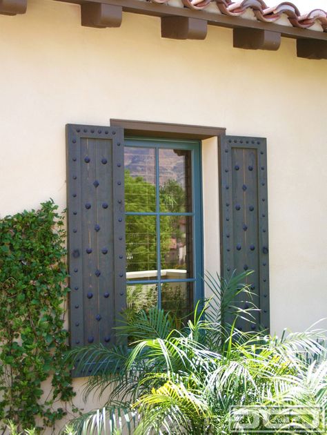 Customized Spanish shutters such as these come in a simple design but the rustic decorative ironwork that is used to embellish these shutters make these shutters a true Spanish architectural accent. Clavos of various sizes as well as diamond head shaped clavos give these shutters their touch of Spanish influence the beautifully stained cedar wood … Spanish Shutters, Mediterranean Shutters, Spanish Style Home Exterior, Stained Cedar, Hacienda Homes, Tuscan Style Homes, House Shutters, Blue Shutters, Rustic Window