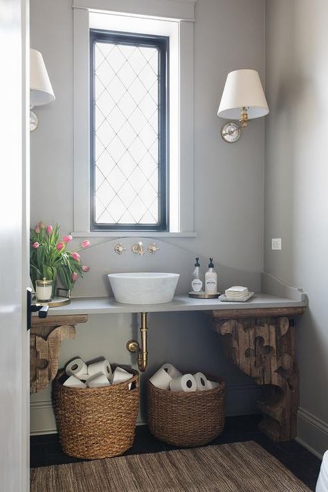 Exquisitely styled cottage bathroom is lit by mirror tiled sconces mounted to a gray wall on either side of a leaded glass window finished with black moldings. Transitional Powder Room, Brass Toilet, White Siding, Powder Room Design, Cottage Bathroom, Bathroom Windows, Mirror Tiles, Paper Storage, Bath Room