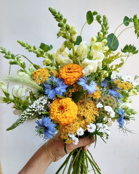 Liisa | Pollenation Blooms on Instagram: "Friday flowers. 💐 A couple of years ago my mom sent me a picture of the Queen wearing an orange and blue hat, as a palette possibility for bouquets, and I've been after it ever since. 💞 👑 • • • #flowerfarmer #horticulturist #stjosephisland #csa #bouquets #marketgarden #cutflowers #cutflowerfarm #saultstemarie #slowflowers #sustainableflowers" Bouquet Colour Palettes, Marigold And Blue Wedding, Orange Bouquet Flowers, June Flowers Wedding, Blue Orange Wedding Theme, Orange Blue Wedding Flowers, Blue And Orange Wedding Bouquet, Blue Fall Flowers, Fake Flower Arrangements Wedding